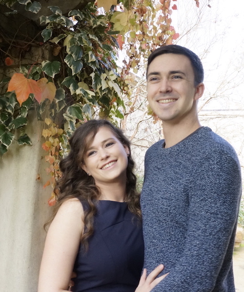 The happy couple under a vine-draped archway